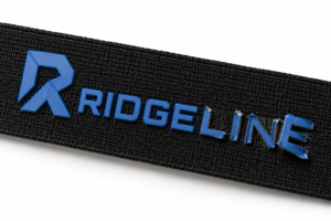 Blue silicone logo peeling off the surface of black webbing