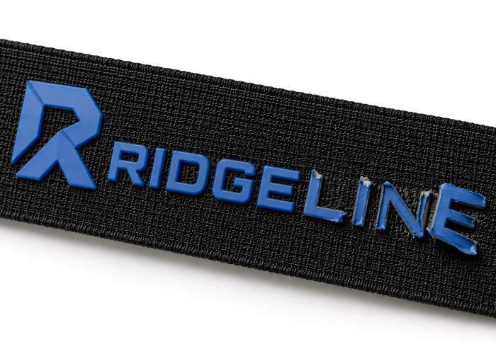 Blue silicone logo peeling off the surface of black webbing
