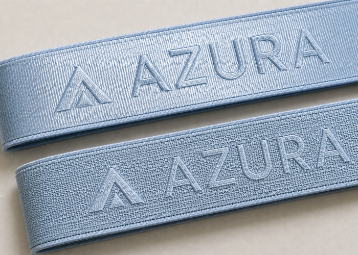 Light blue sports bra straps showing different woven logo surface finishes